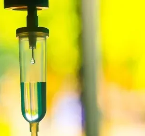 Close-up of a medical IV drip chamber with fluid.