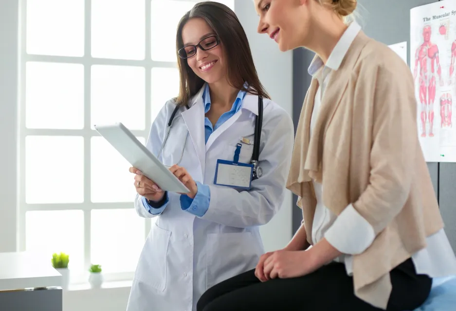 Female doctor showing patient information on a tablet.