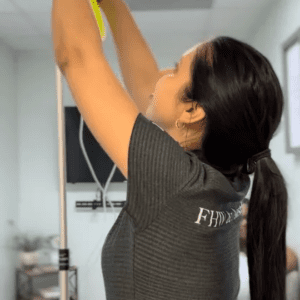 Woman reaching upward indoors, wearing a dark shirt.