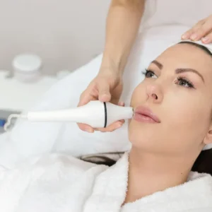 A woman receiving a facial treatment with a handheld device.