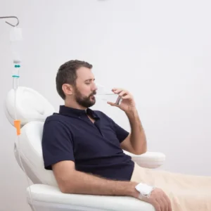 Man relaxing in a chair while drinking a beverage.