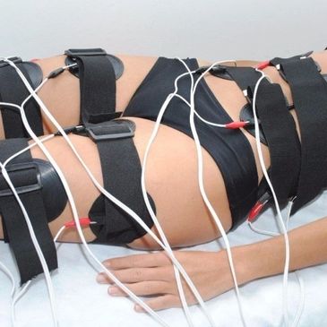 Person undergoing electrical muscle stimulation therapy lying on a bed.