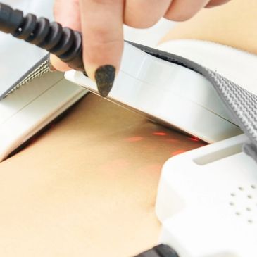 A hand holding an ultrasound probe on a person's abdomen.