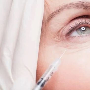 Close-up of a syringe near a woman's eye.
