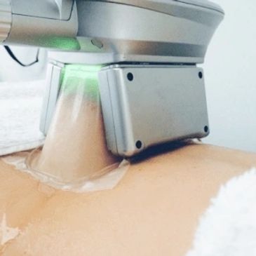 A close-up of a medical device on a person's skin emitting green light.