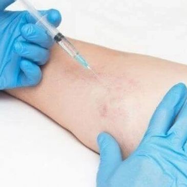 A gloved hand injecting a substance into an arm.