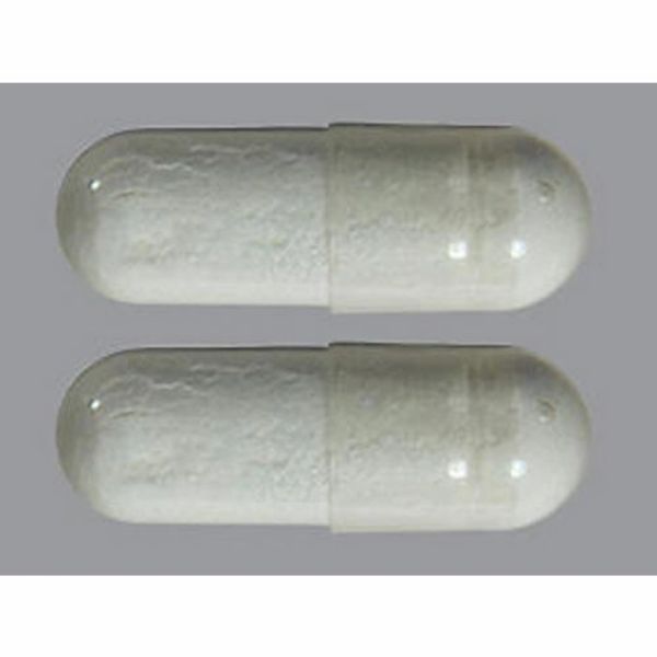 Close-up of two white capsules on a gray surface.